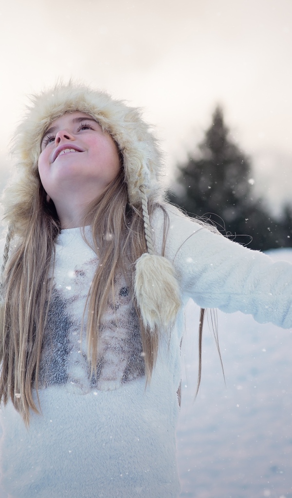 Девочка в белой шапке радуется снегу