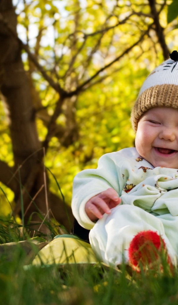 Смеющийся грудной ребенок сидит на траве