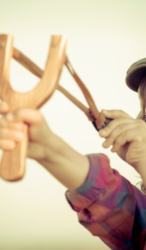 Маленький мальчик в кепке целится с рогатки