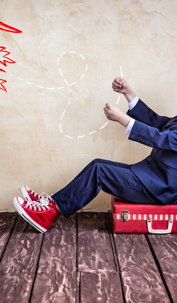 Маленький мальчик в шлеме сидит на чемодане