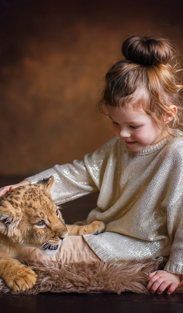 Маленькая девочка гладит маленького львенка