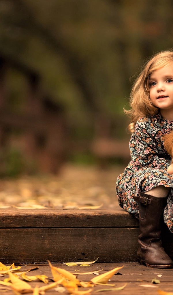 Маленькая девочка с золотистым ретривером сидит на мосту