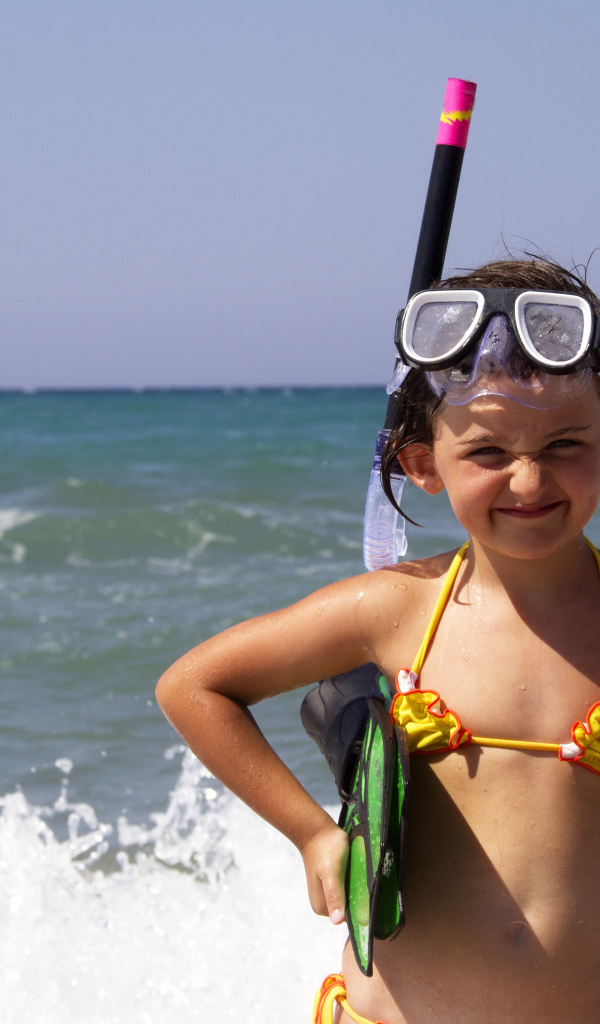 Маленькая девочка в очках и с ластами на море