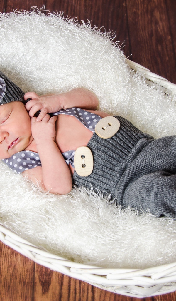 Спящий младенец в сером костюме в белой корзине