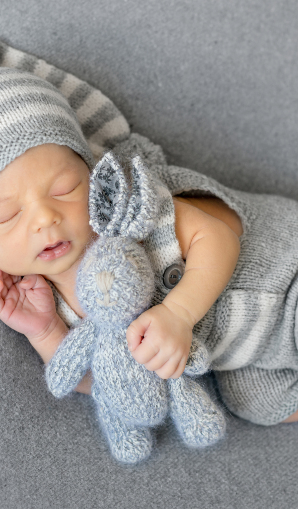 Спящий младенец с серым вязаным зайцем