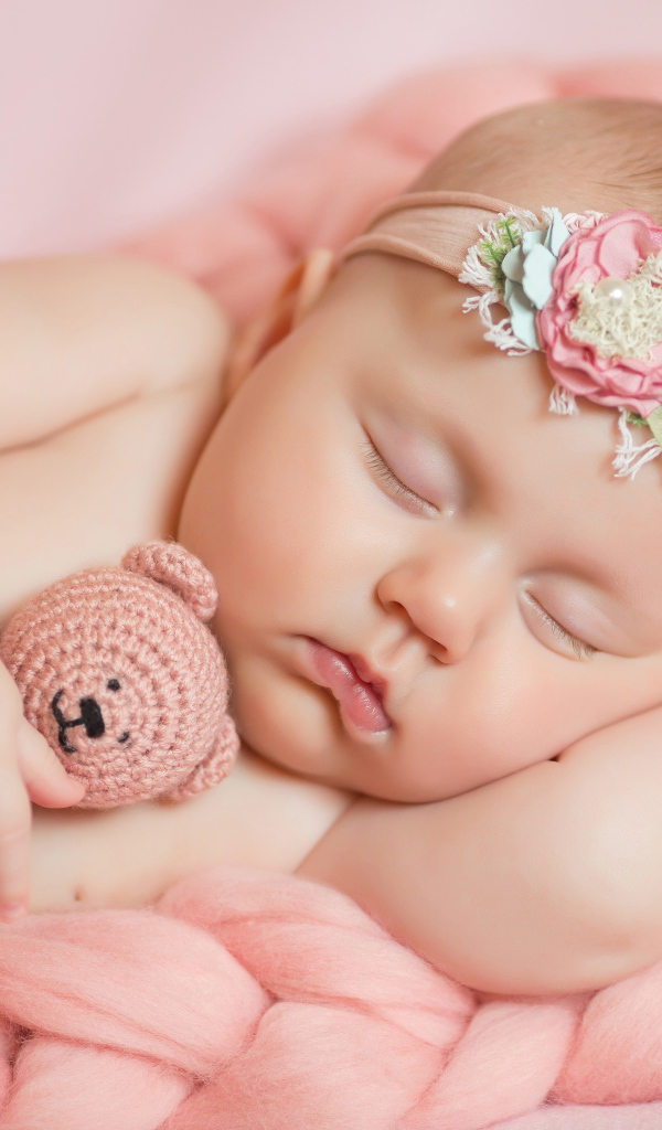 Спящая маленькая девочка с вязаным медвежонком в руке