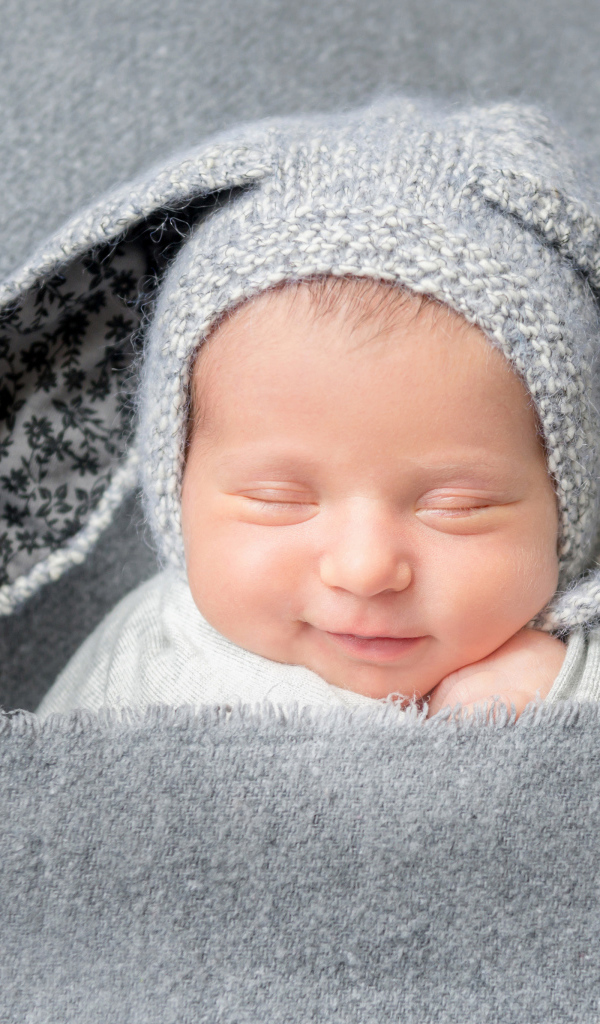 Маленький грудной ребенок в серой шапке с ушками