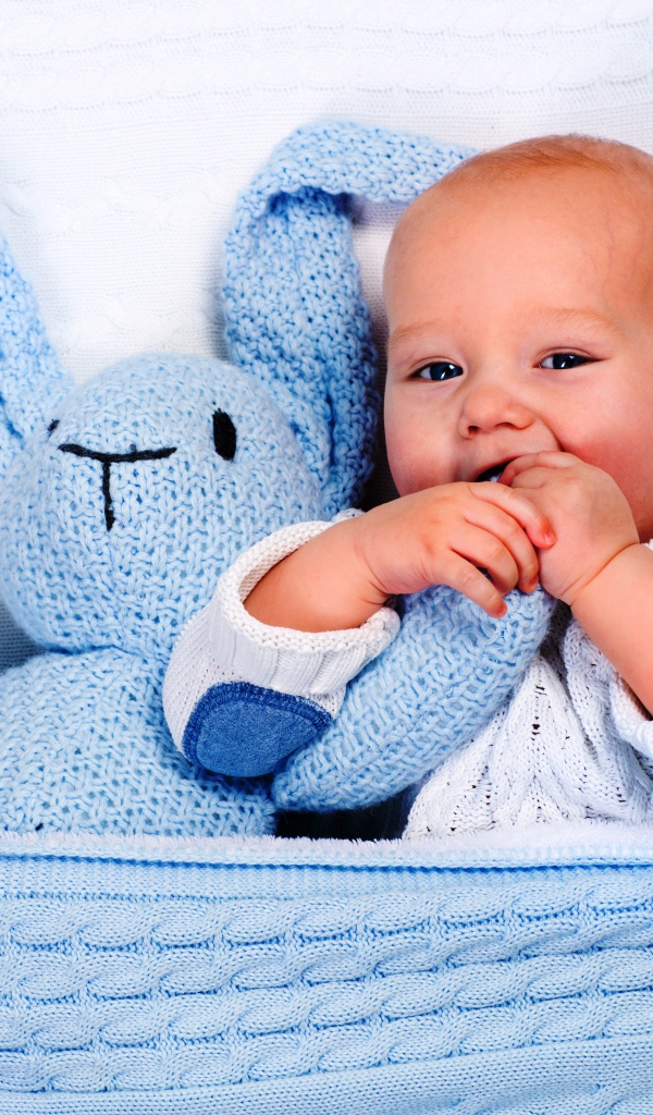 Маленький грудной ребенок грызет мягкую игрушку 