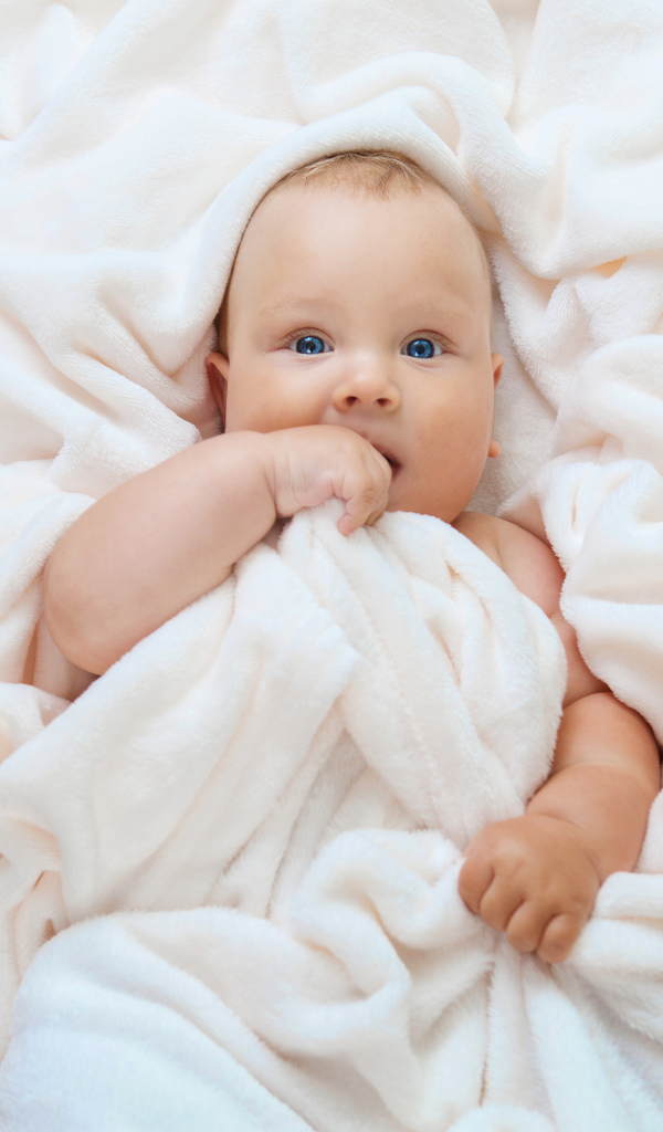 Маленький голубоглазый ребенок в покрывале 