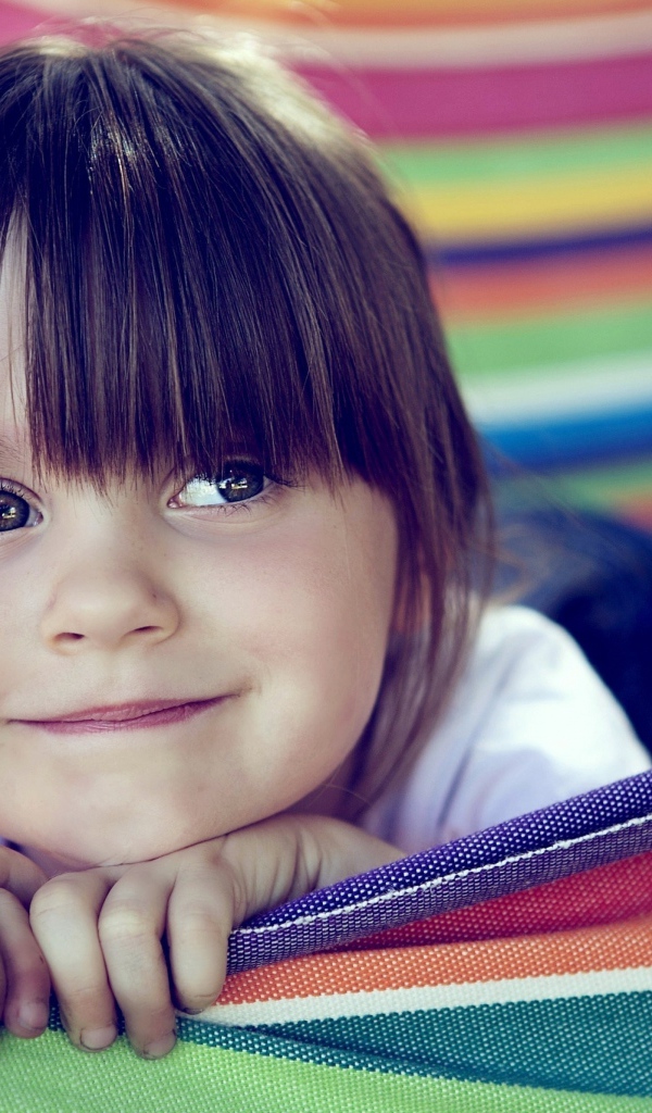 Маленькая кареглазая девочка лежит в гамаке