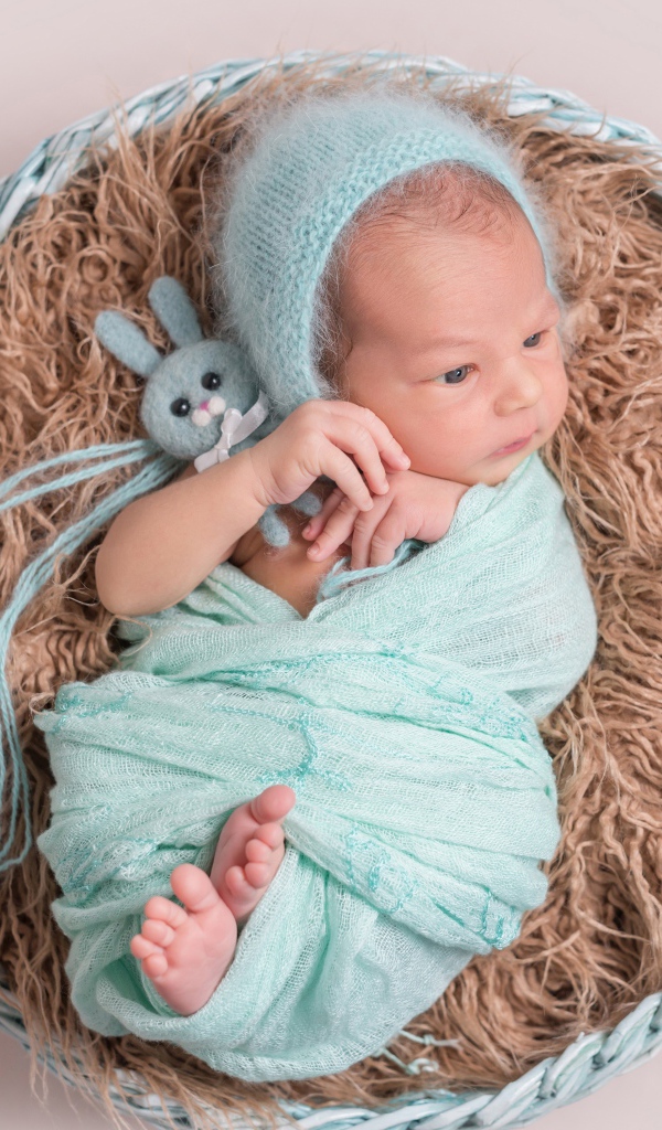 Маленький ребенок в корзине на сером фоне