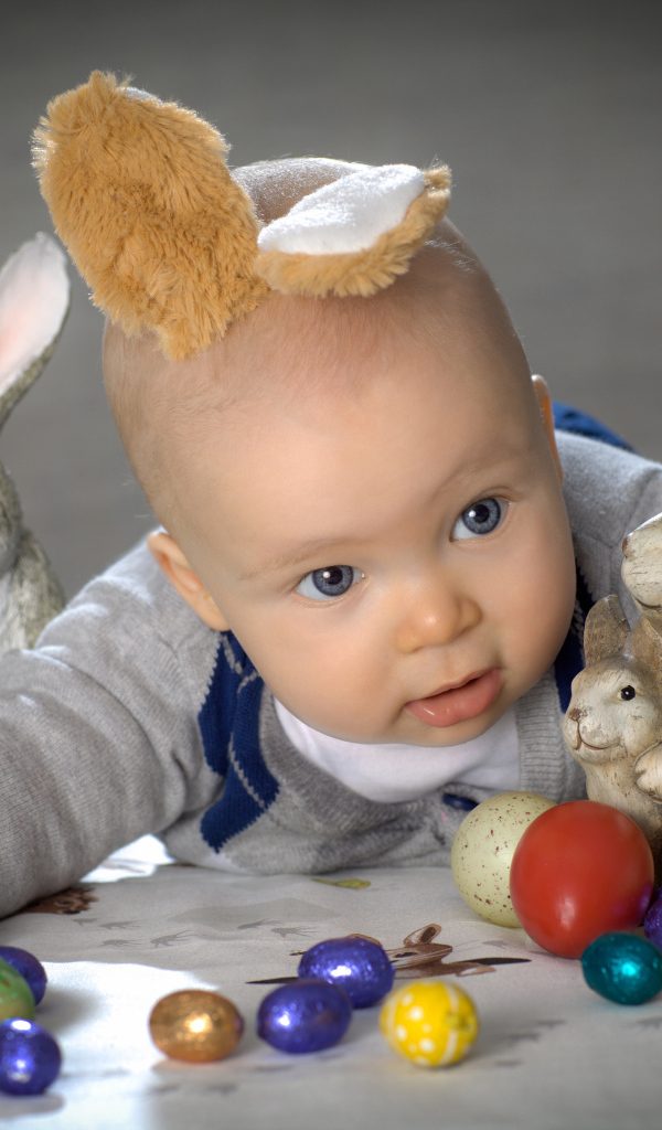 Маленький ребенок с пасхальными кроликами и яйцами