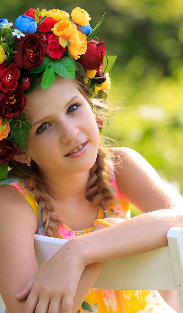 Красивая девочка с венком на голове сидит на стуле