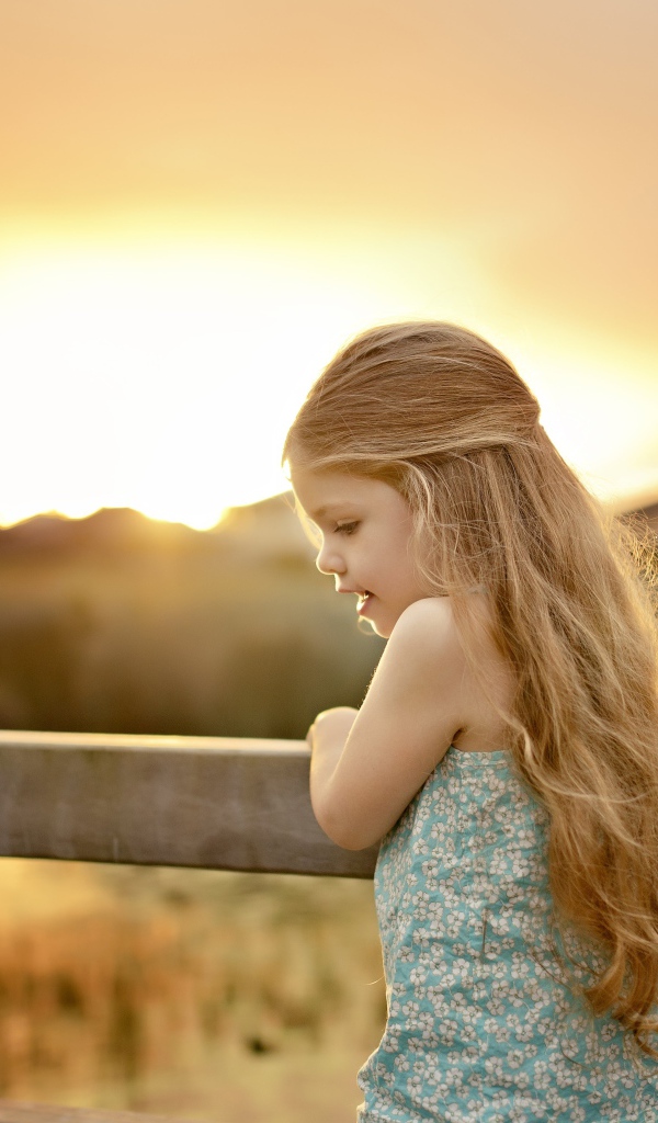 Красивая маленькая девочка на закате солнца
