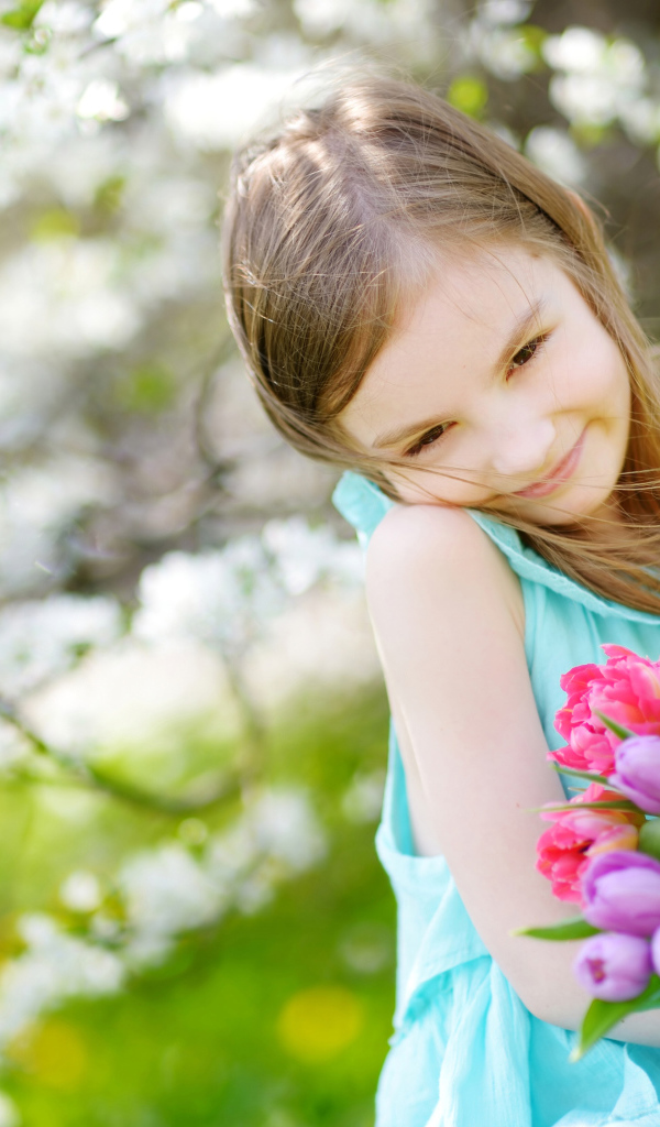 Красивая маленькая девочка с букетом тюльпанов весной