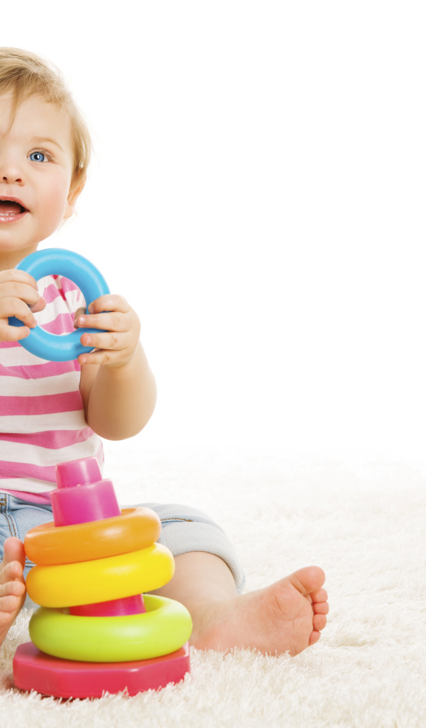 Голубоглазый маленький мальчик с игрушкой на белом фоне