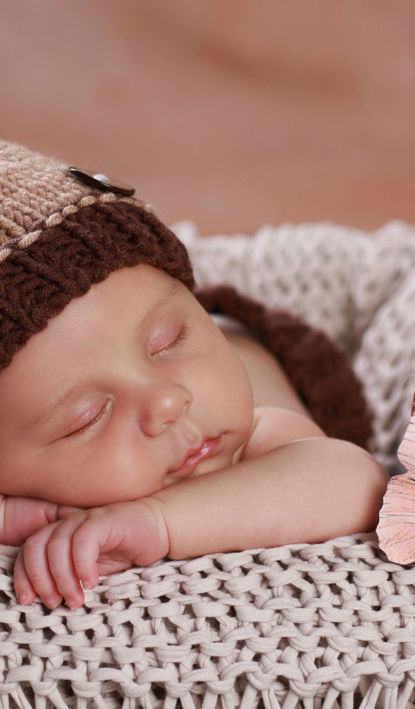Милый спящий ребенок в коричневой вязаной шапке 