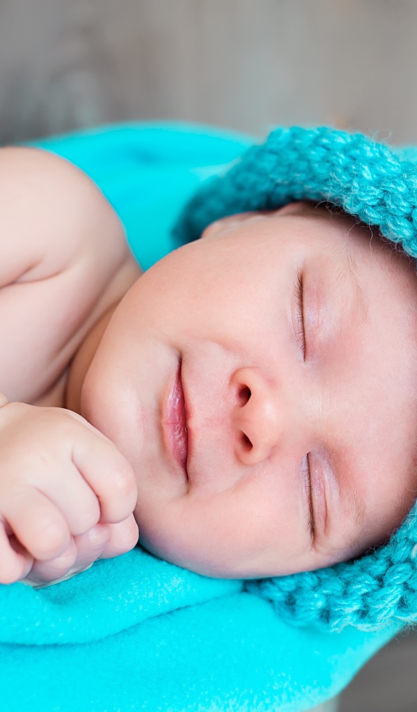 Милый спящий ребенок в голубой вязаной шапке