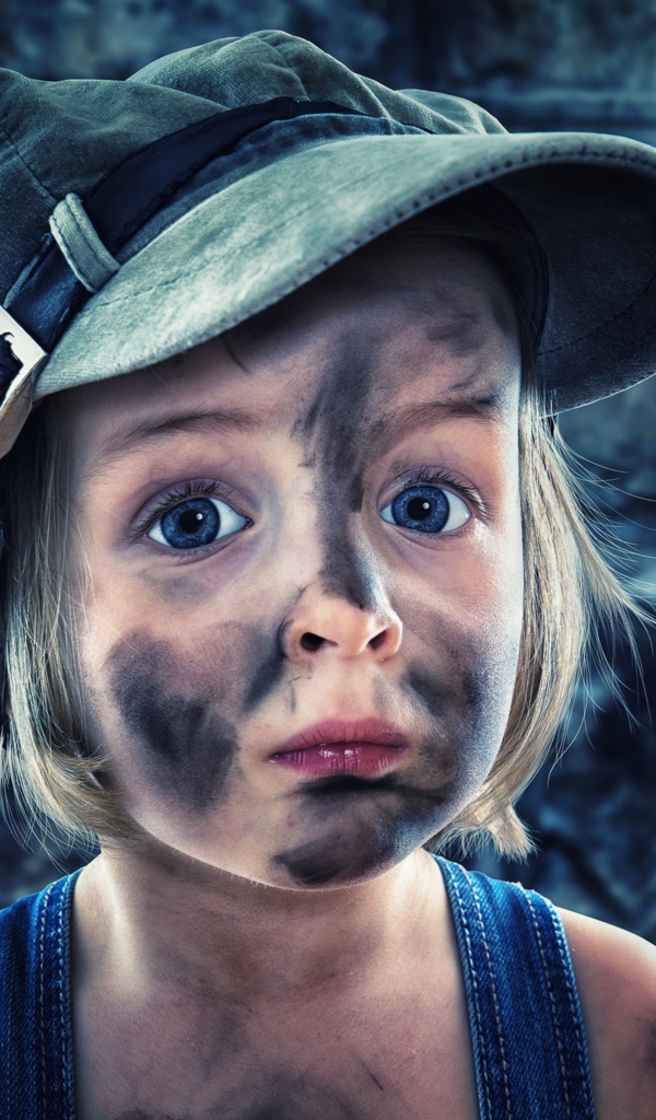 Смешная девочка в кепке с грязным лицом