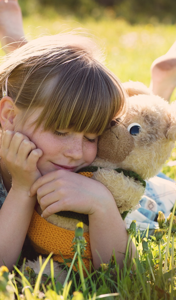 Девочка лежит на траве с игрушкой