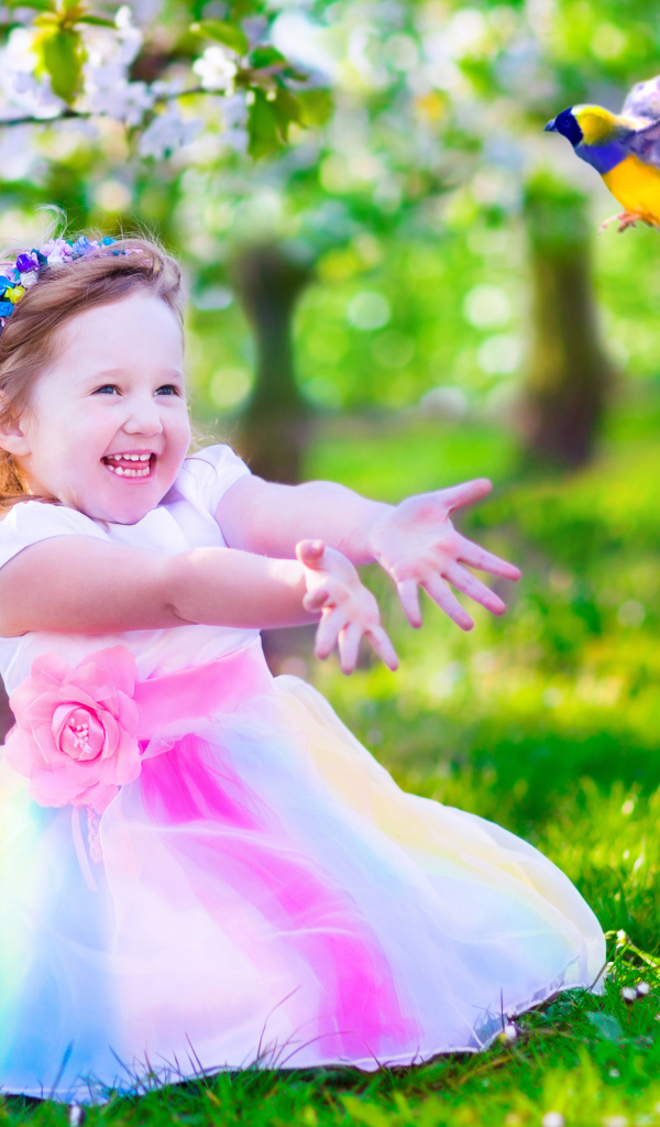 Смеющаяся маленькая девочка в красивом платье на зеленой траве