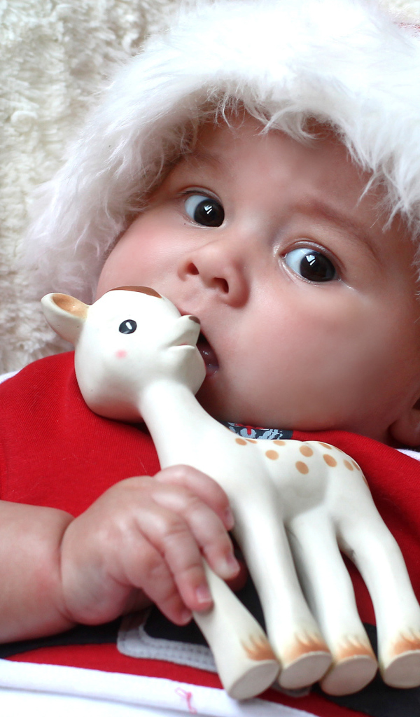 Маленький ребенок в новогодней шапке с игрушкой в руке