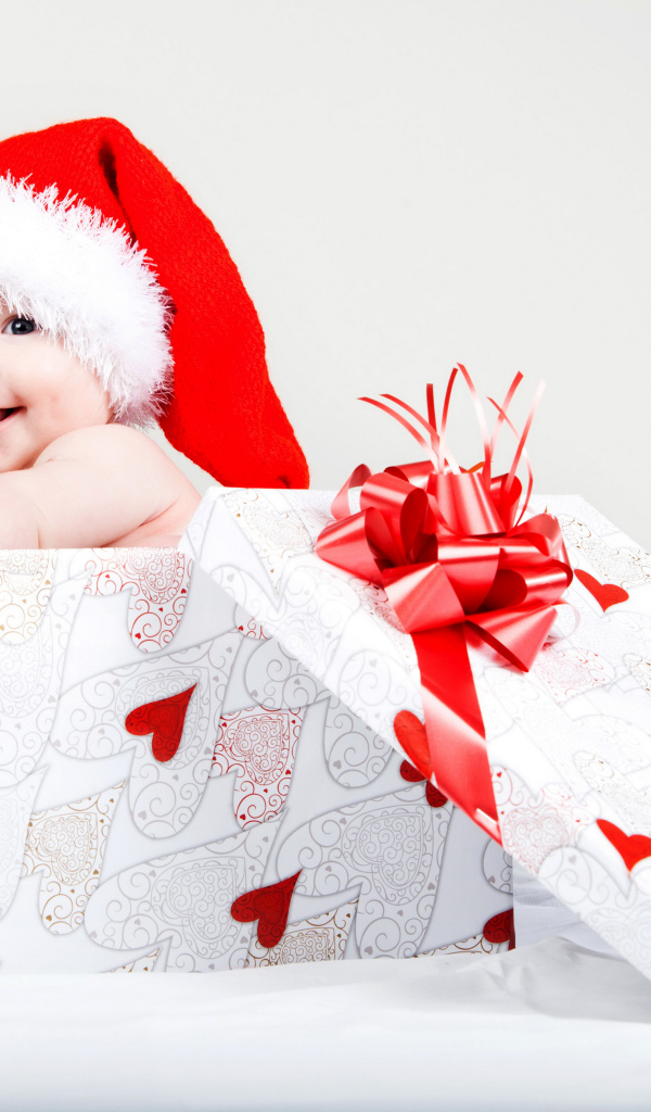 Маленький ребенок в новогоднем костюме в коробке для подарка на сером фоне