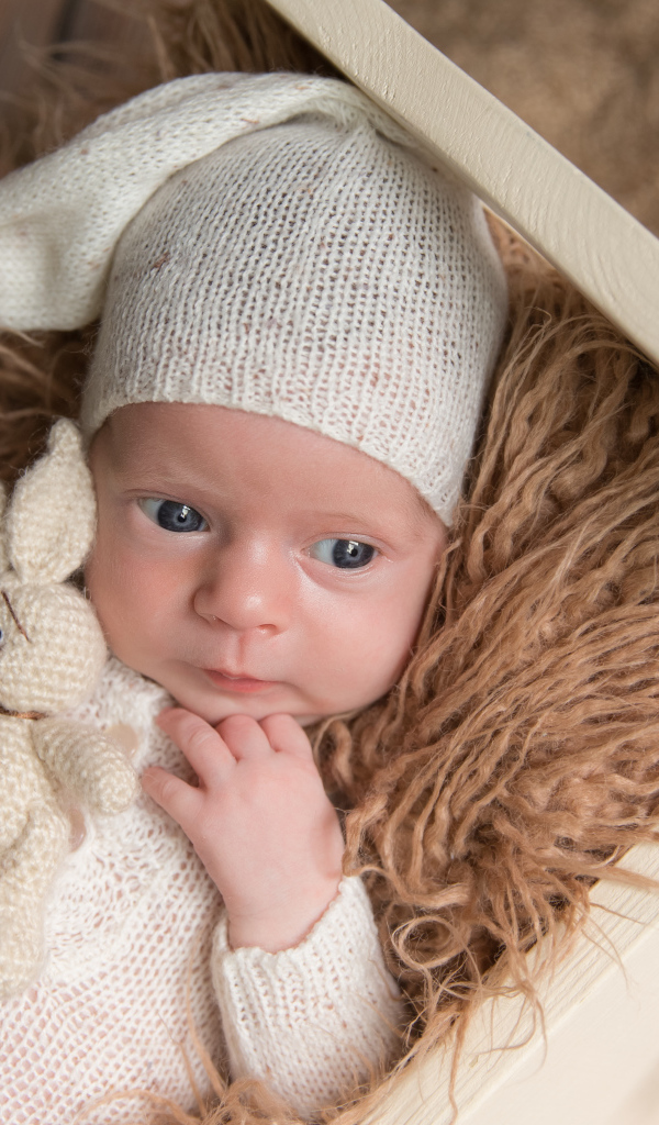 Маленький ребенок в вязанном костюме с зайчиком