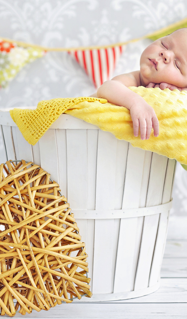 Маленький ребенок спит в корзине с плетеным сердцем