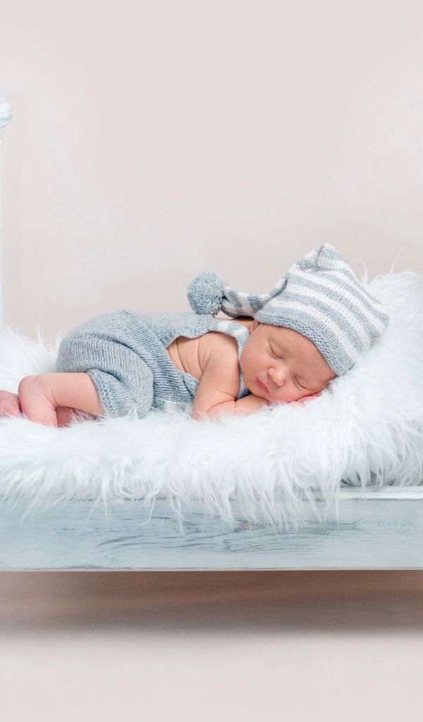 Маленький грудной ребенок спит в маленькой кроватке