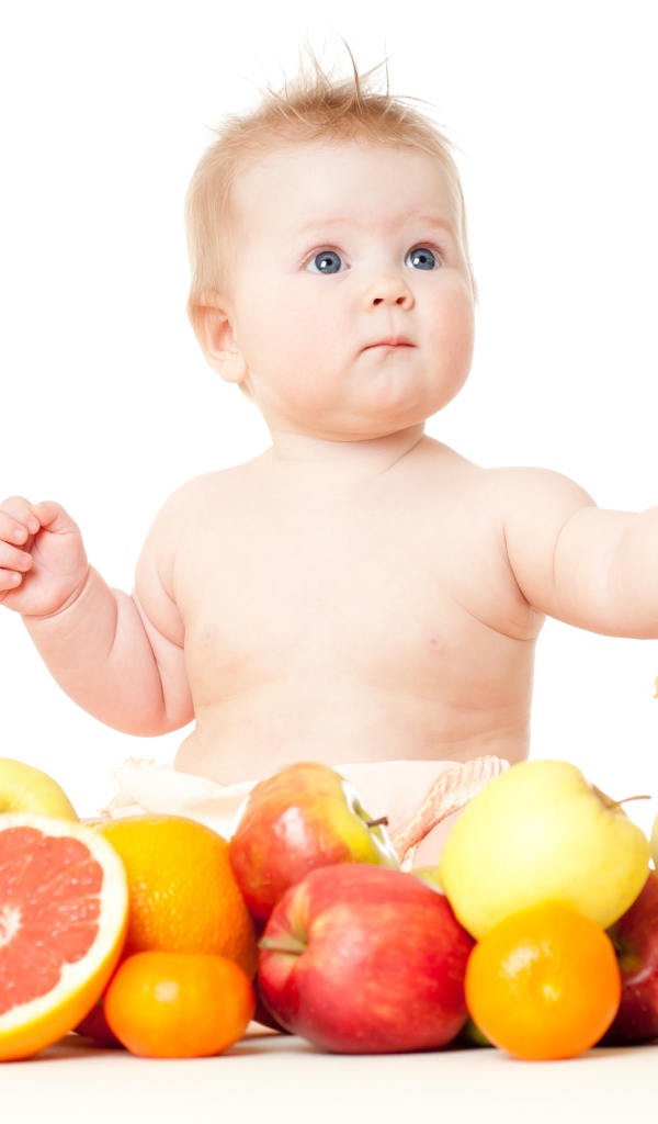 Маленький голубоглазый ребенок с фруктами на белом фоне