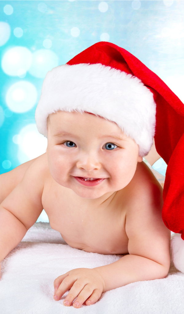 Маленький голубоглазый ребенок в красном новогоднем колпаке