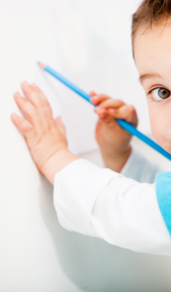 Маленький мальчик рисует карандашом на стене