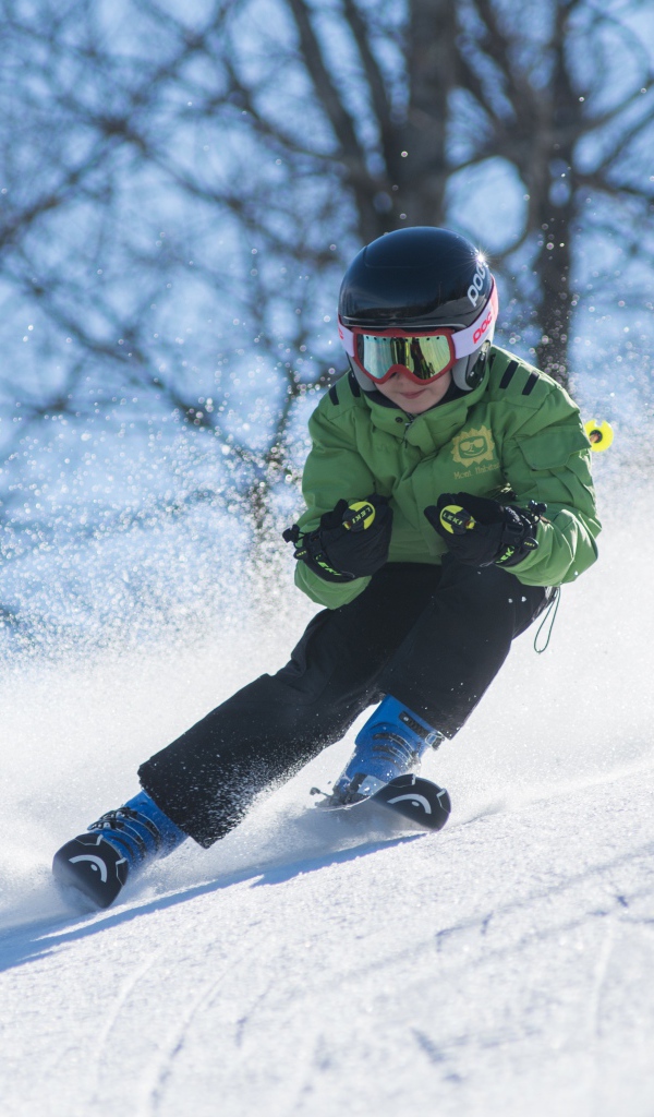 Маленький мальчик спускается с горы на лыжах