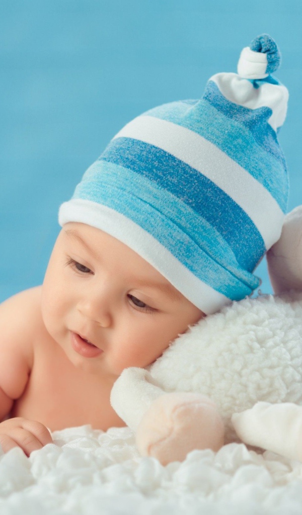 Маленький мальчик в голубой шапке с игрушкой 