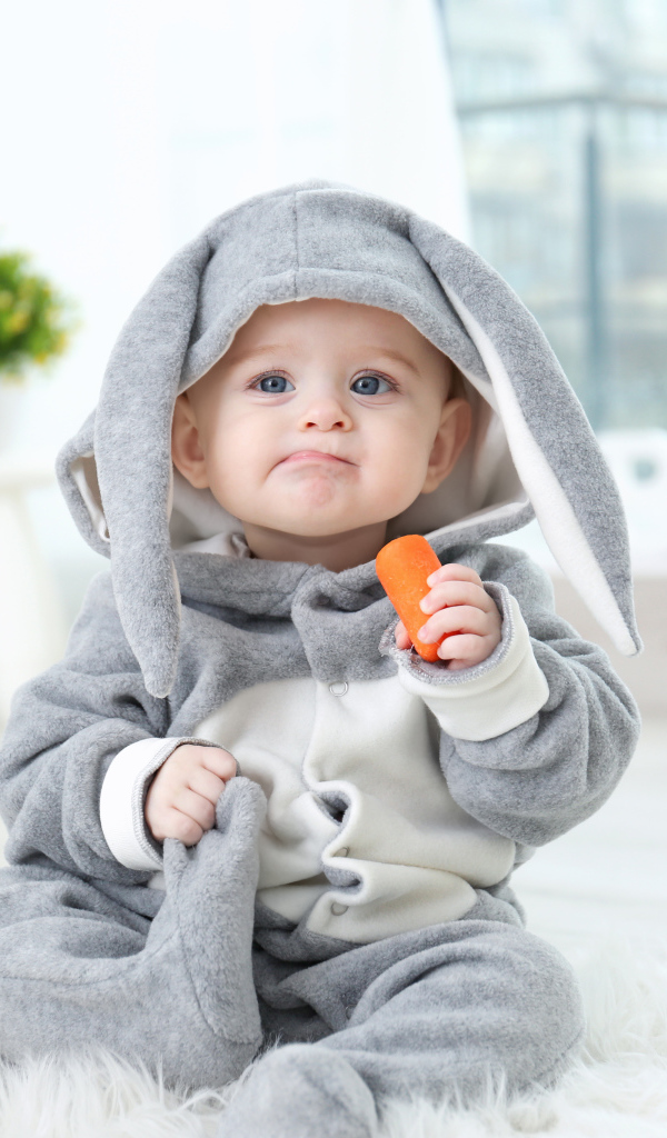 Маленький мальчик в костюме зайчика с морковкой в руке