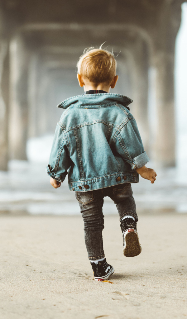 Маленький мальчик в джинсовой куртке спиной