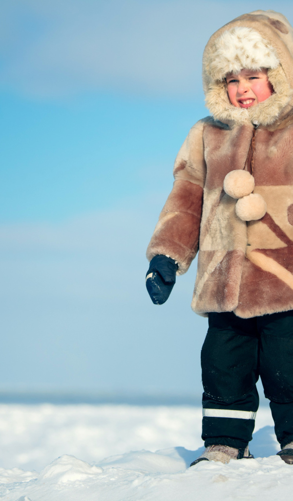 Маленький мальчик в теплой шубе на снегу 