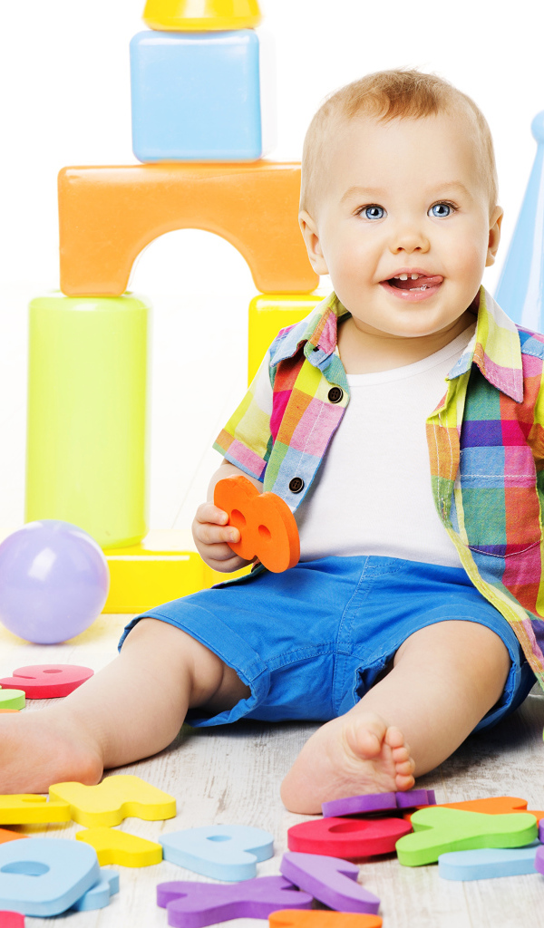 Маленький мальчик играет с разноцветными игрушками 