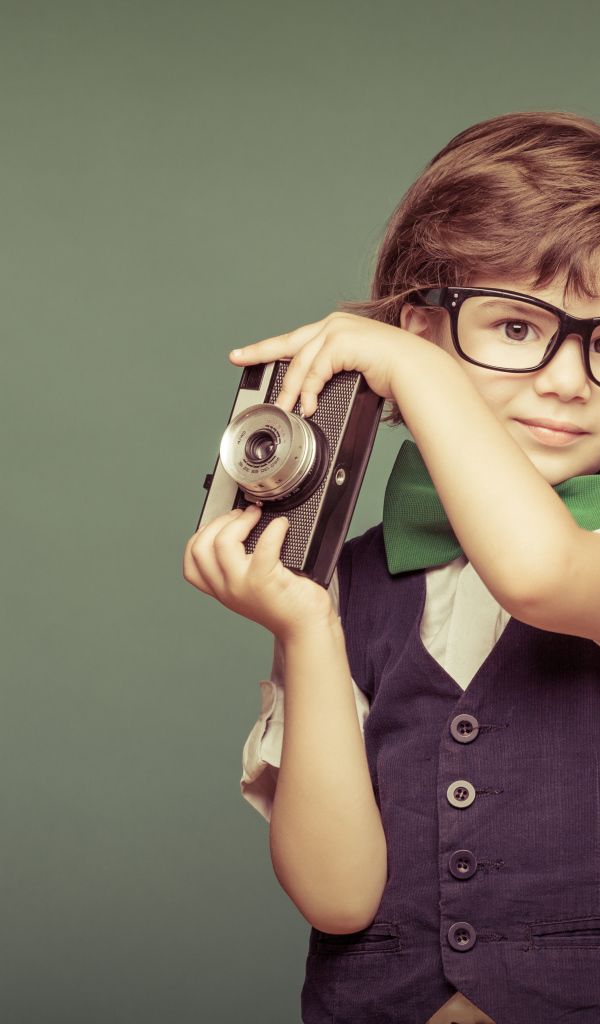 Маленький мальчик в очках с фотоаппаратом