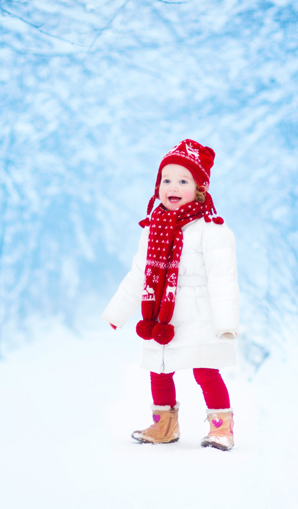 Маленькая веселая девочка в зимнем лесу