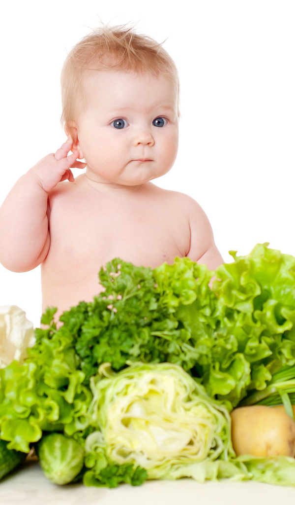 Маленький ребенок с овощами и зеленью на белом фоне