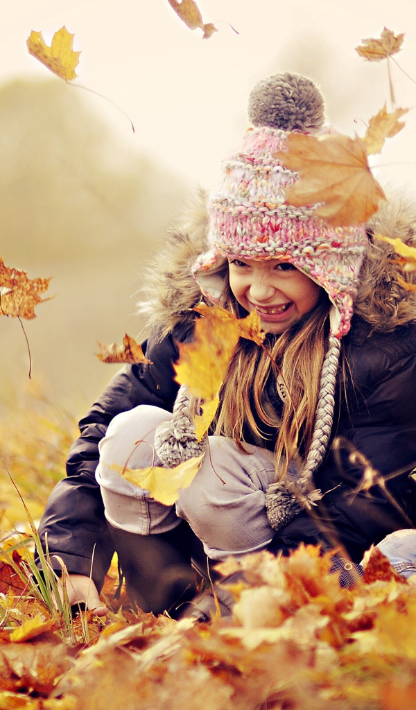 Маленькие дети играют на опавшей желтой листве осенью