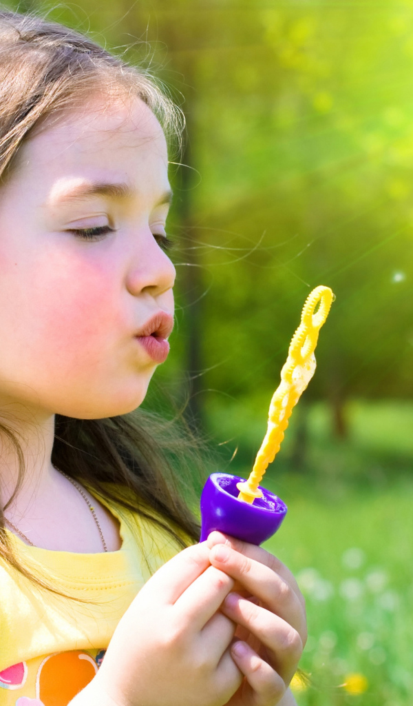 Маленькая девочка пускает мыльные пузыри