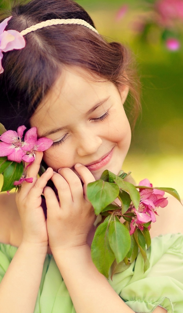 Маленькая девочка обнимает ветку с розовыми цветами