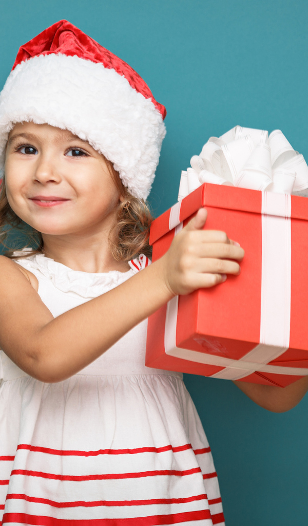 Маленькая девочка в новогоднем костюме с подарком на голубом фоне