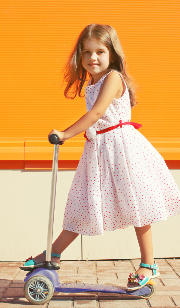 Маленькая девочка в платье на самокате 