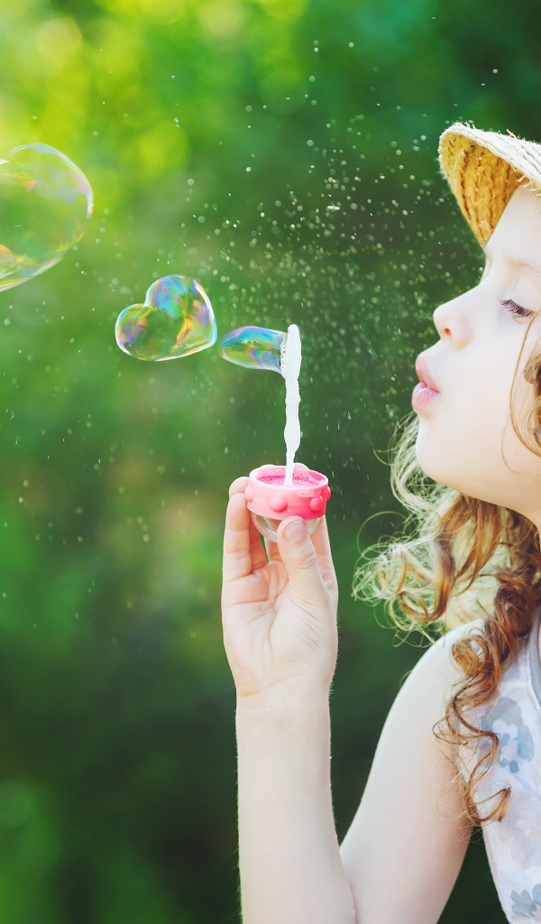 Маленькая девочка в шляпе с мыльными пузырями