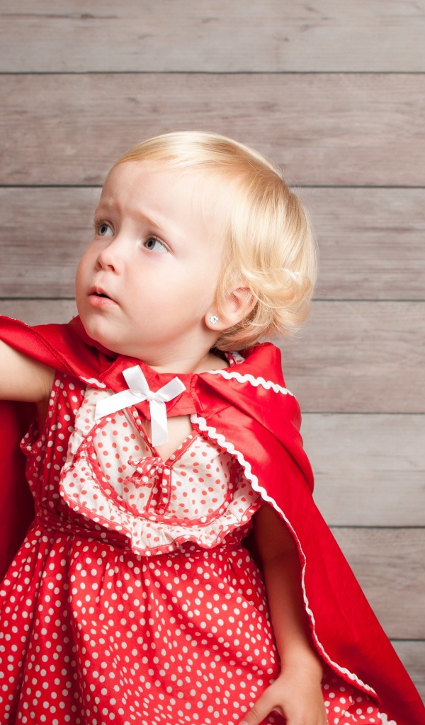 Маленькая девочка в красном платье ловит мыльный пузырь