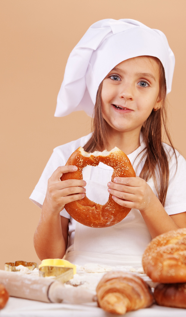 Маленькая девочка в костюме повара и свежей выпечкой